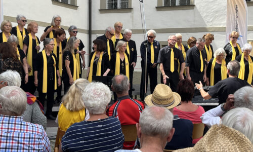 the sweet60s mit Chorleiter Michael Armann bei den Chortagen 2024 in Füssen. Solistin Roswitha Gabner begrüßt das Publikum im Klosterhof.