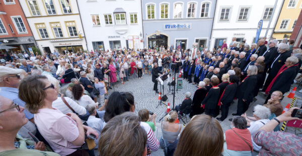 the sweet60s auf den Stufen der Landsberger Stadtpfarrkirche Mariä Himmelfahrt umringt von erwartungsvollen Zuschauern Erwartungsvolles Publikum umringt den Konzertchor. Der Landsberger Gospelchor the sweet60s beleben mit einem Freundschaftskonzert auf dem Georg-Hellmeier-Platz die Städtepartnerschaft zwischen Landsberg und der südfranzösischen Küstenstadt Saint-Laurent-du-Var